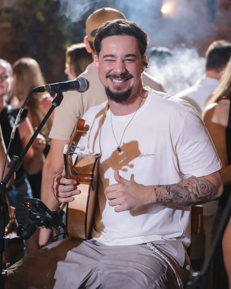 Alex Júnior sorrindo com o banjo no show